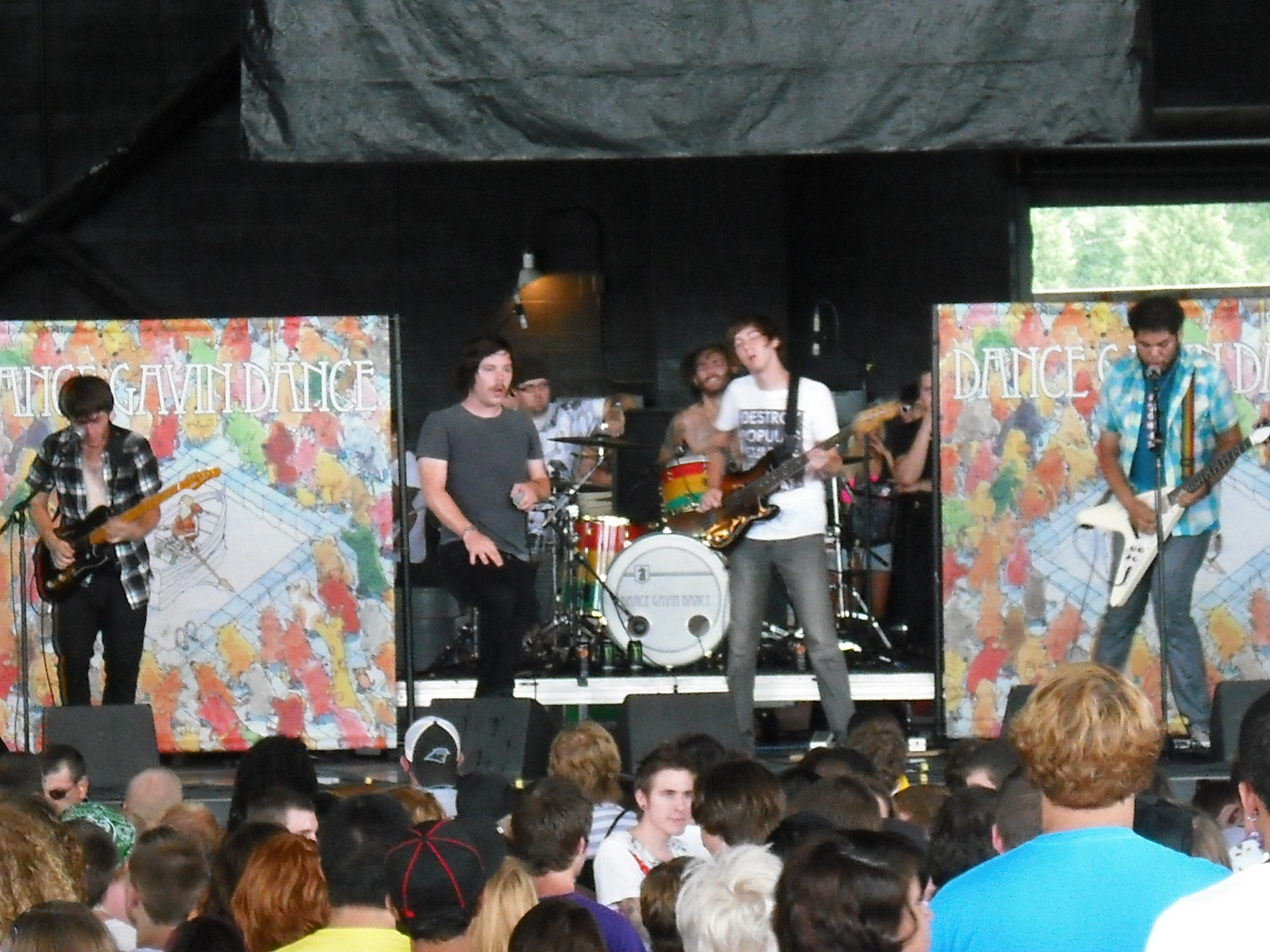 Banda tocando num palco ao ar livre do Warped Tour, com o público na frente